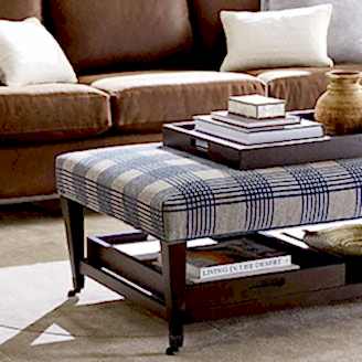 Plaid ottoman in front of brown sofa